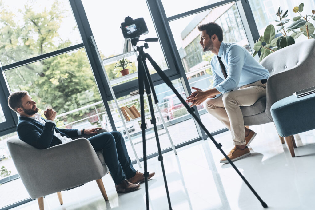 Creating interesting content. Two young men in smart casual wear talking while making new video indoors