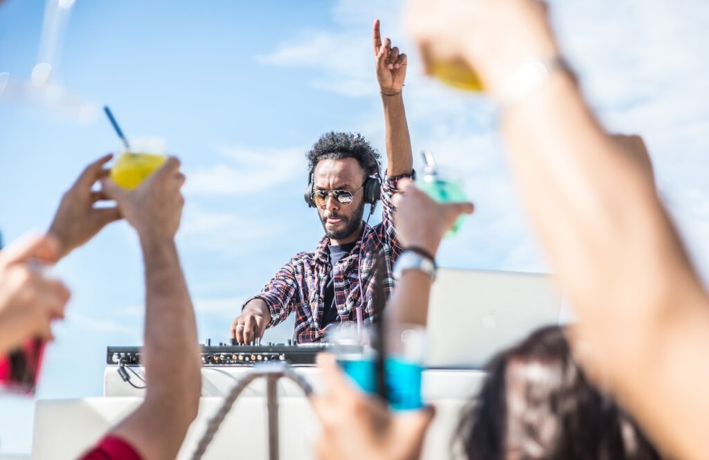 dj set at the beach party. dj spins the music and people is excited with hands up. concept about party, music and people